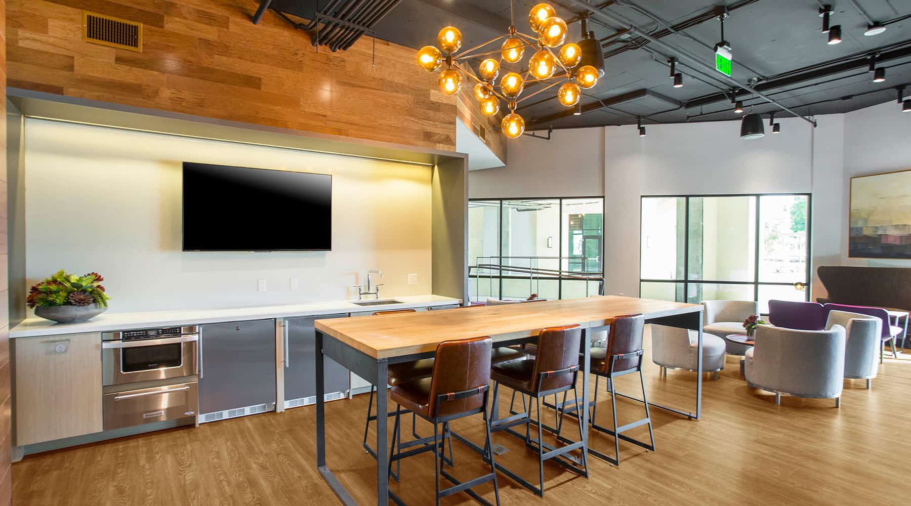 Modern kitchen and lounge area in an apartment with a wooden table and stylish lighting.