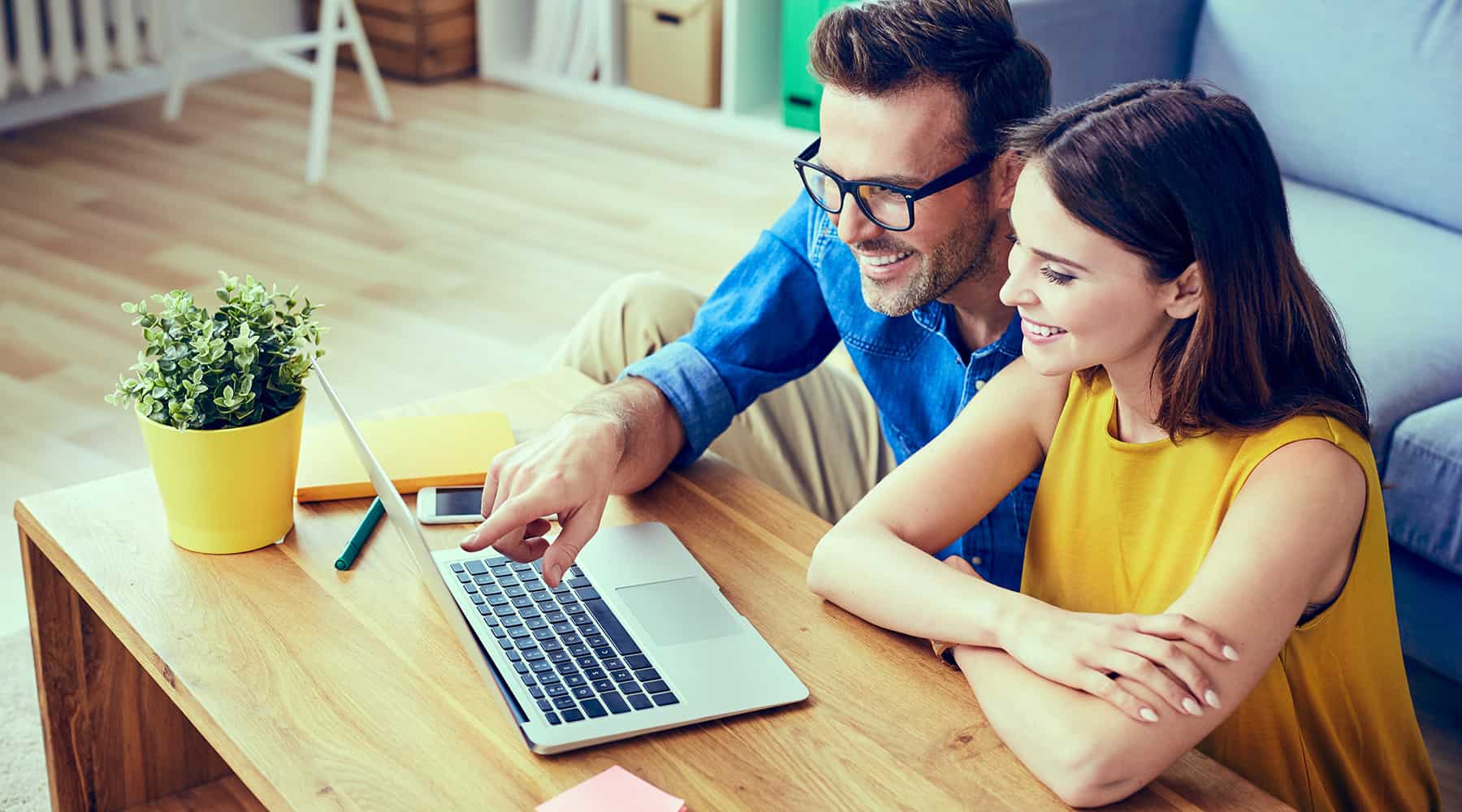 Couple working together on a laptop in a cozy living room.