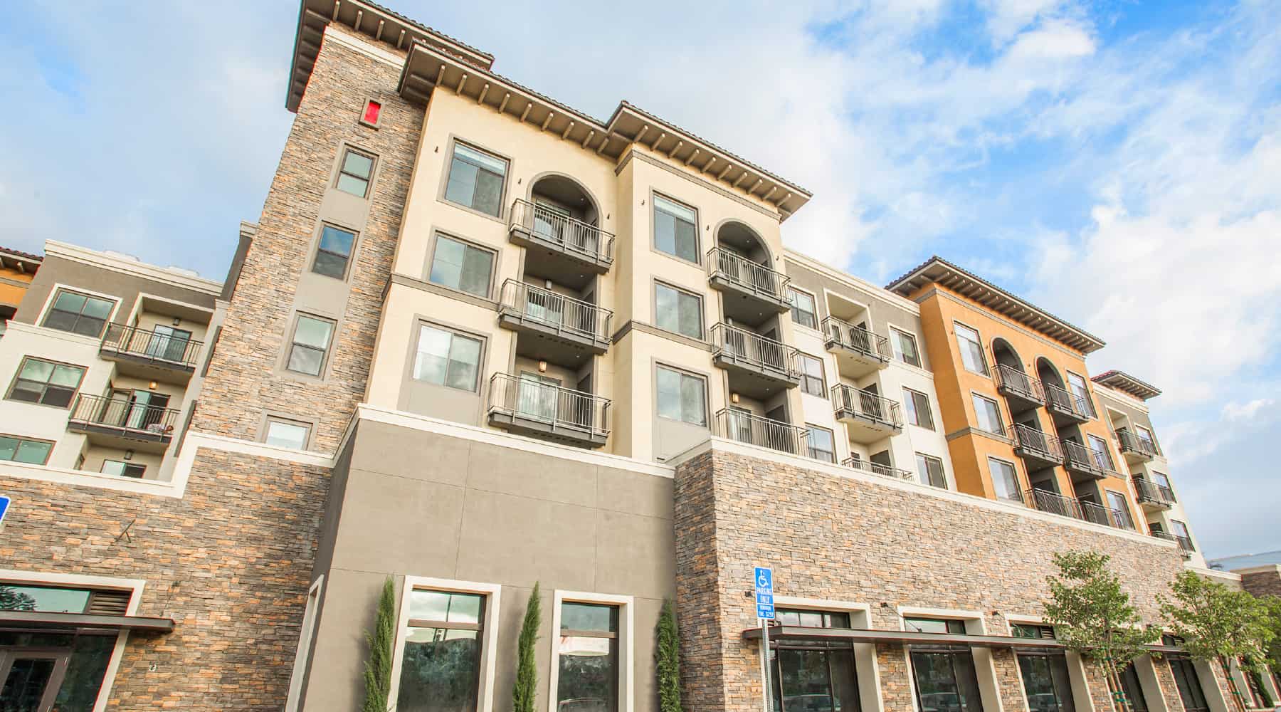 Apartment exterior showcasing a modern building with stone accents and balconies.