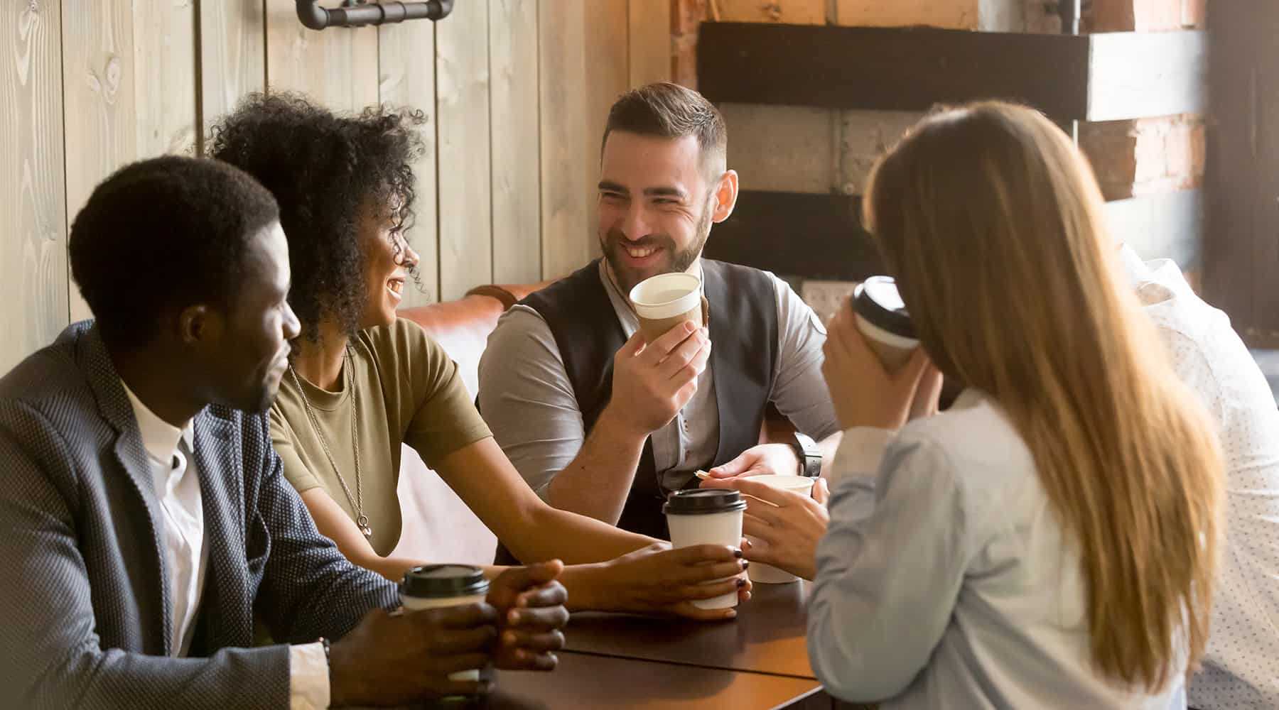 Group of friends sitting at a table in a cafe, drinking coffee and chatting.