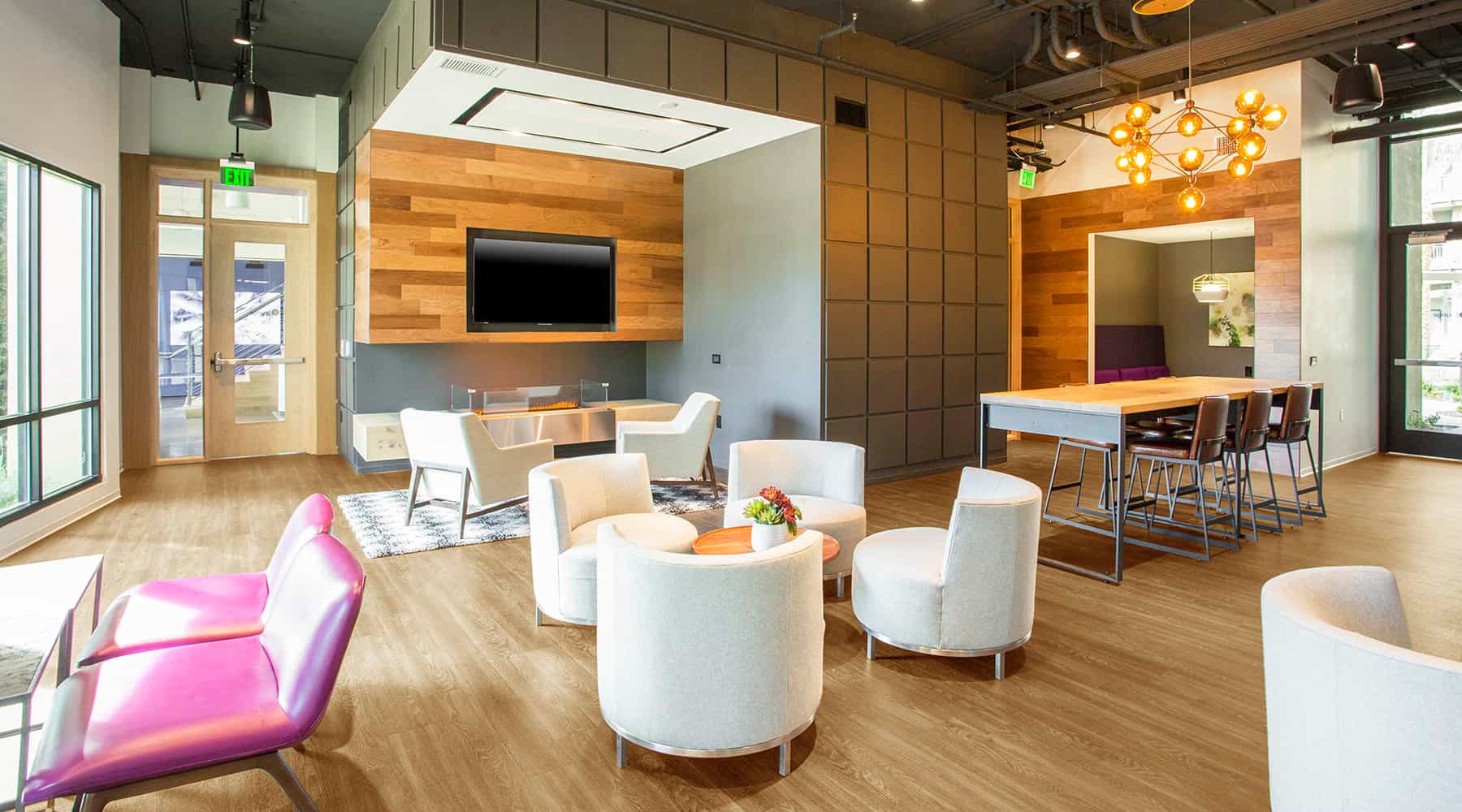 Modern lounge area with seating and a dining table in an apartment building's community space.