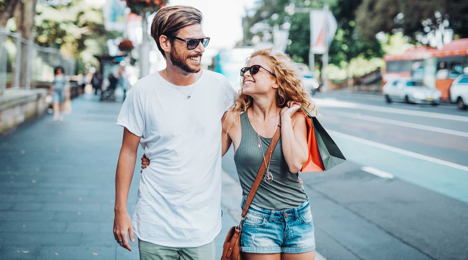 Happy couple walking down the street holding hands and enjoying a sunny day.