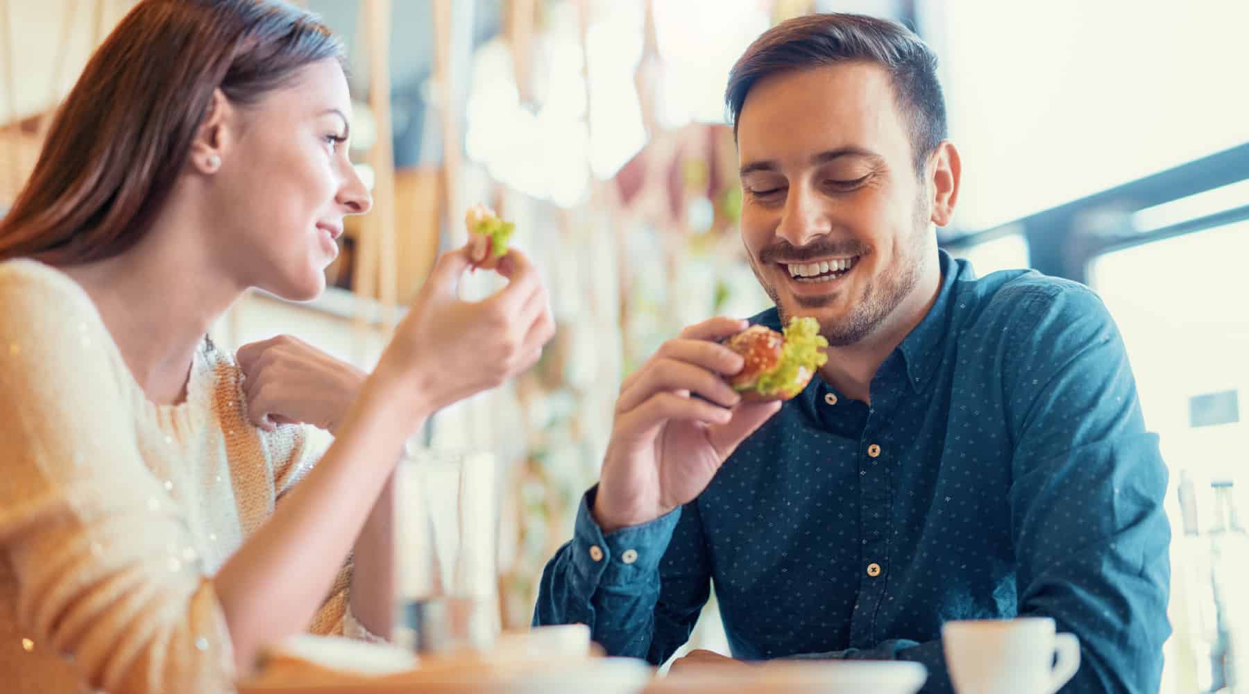 A cheerful couple enjoying small bites of food together at a cozy dining spot