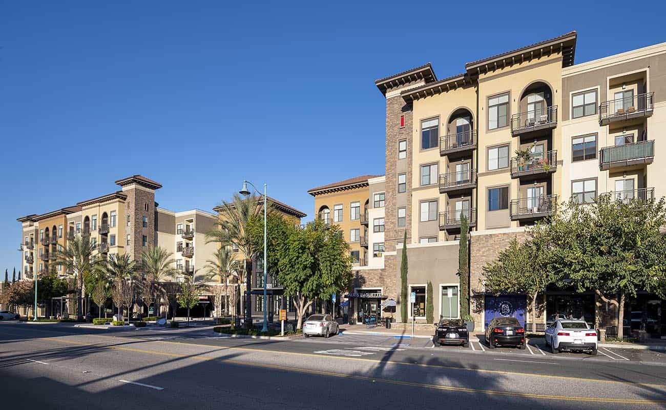 Apartment exterior with palm trees and a clear sky.