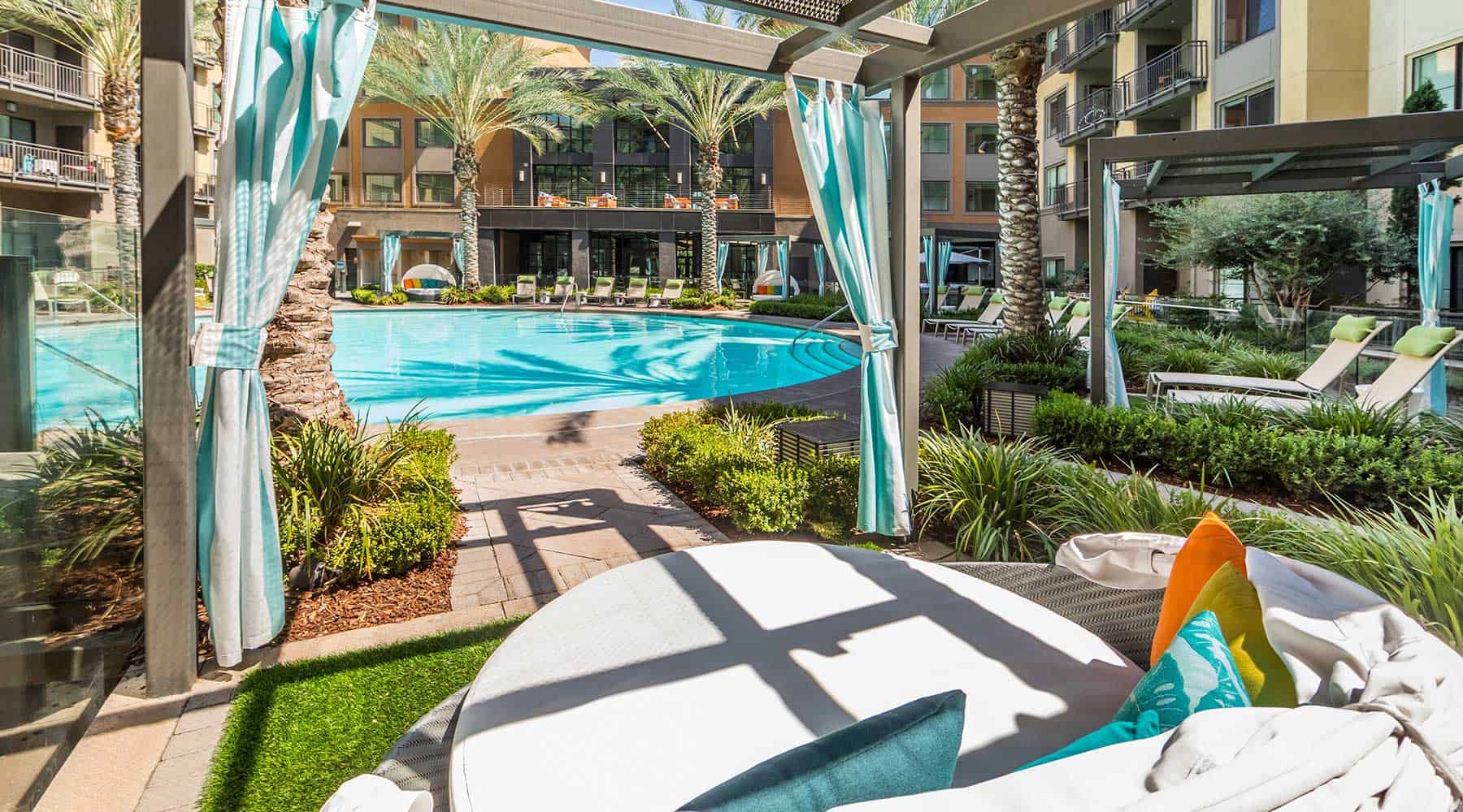 Outdoor lounge area at The Colony in West Covina with a pool view and shaded seating under a pergola.